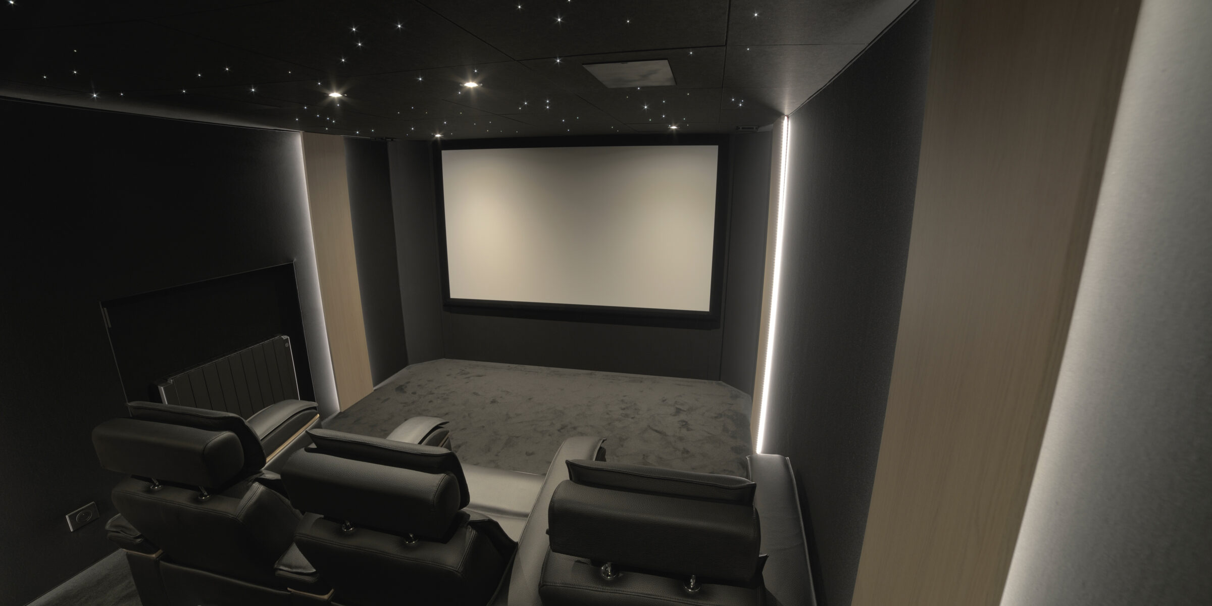 Salle de cinéma privée 17m2 avec 5 fauteuils en cuir noir, ciel étoilé, spots, panneaux décor chêne rétro-éclairés à Créteil