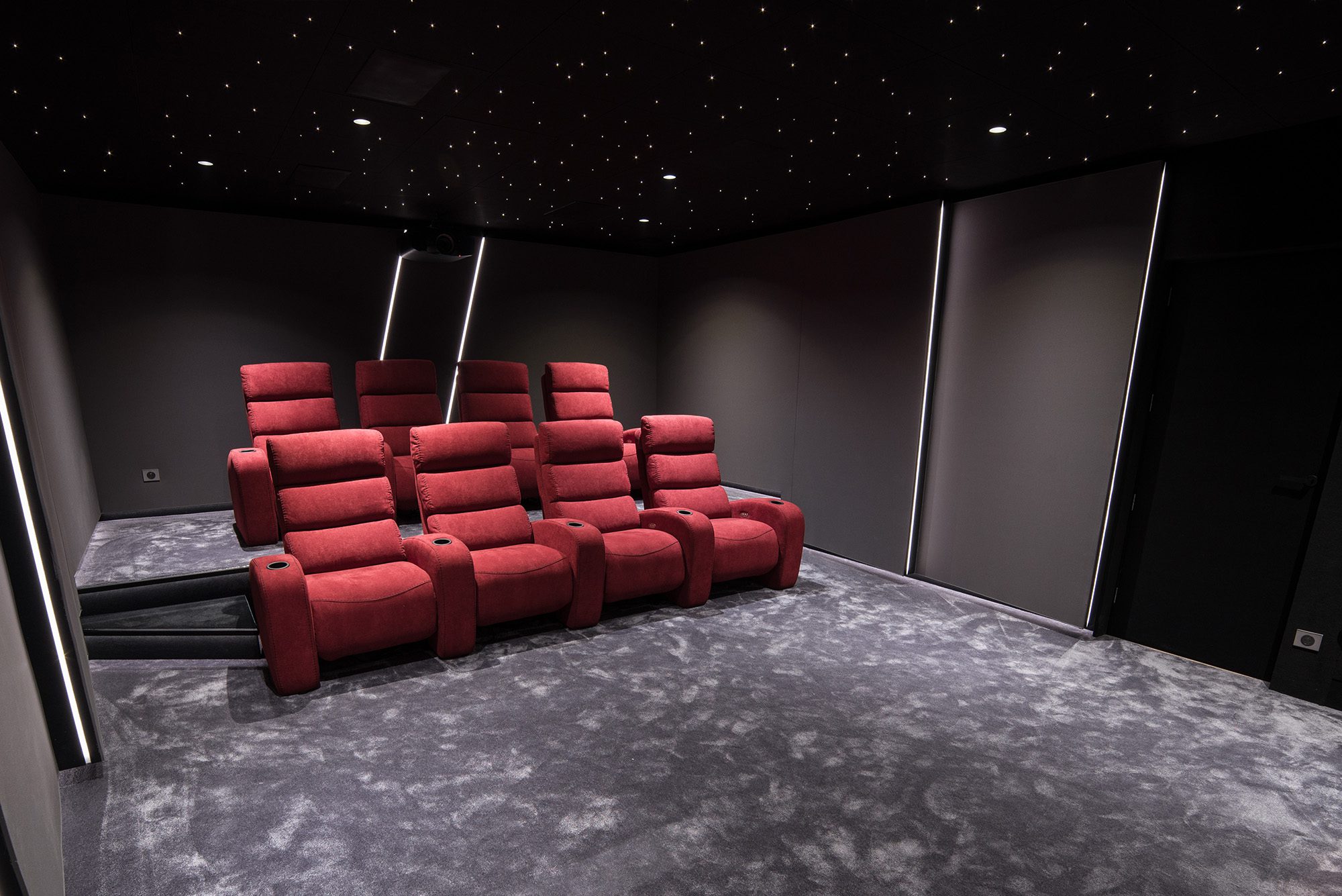 Salle de cinema privée 35m2 rouge 9 places, fauteuils en tissu rouge, tissu tendu gris anthraacite, avant-scène, ciel étoilé, spots, panneaux lumineux au Havre