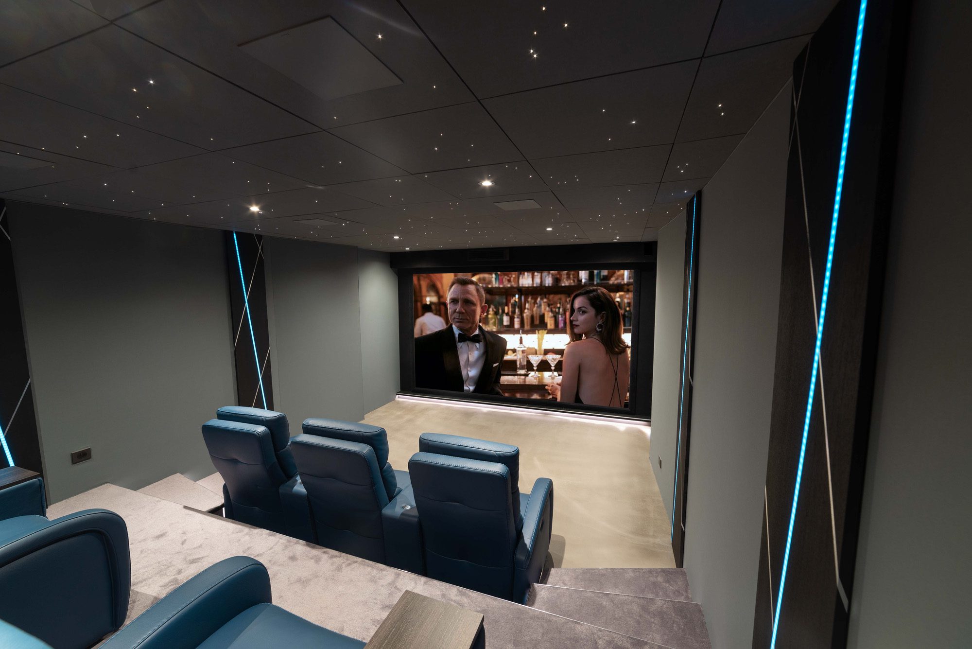 Salle de cinéma privée 32m2, 7 places, fauteuils en cuir bleu, vant-scène, ciel étoilé, panneaux décor en chêne éclairés par un ruban led RGB à Meaux