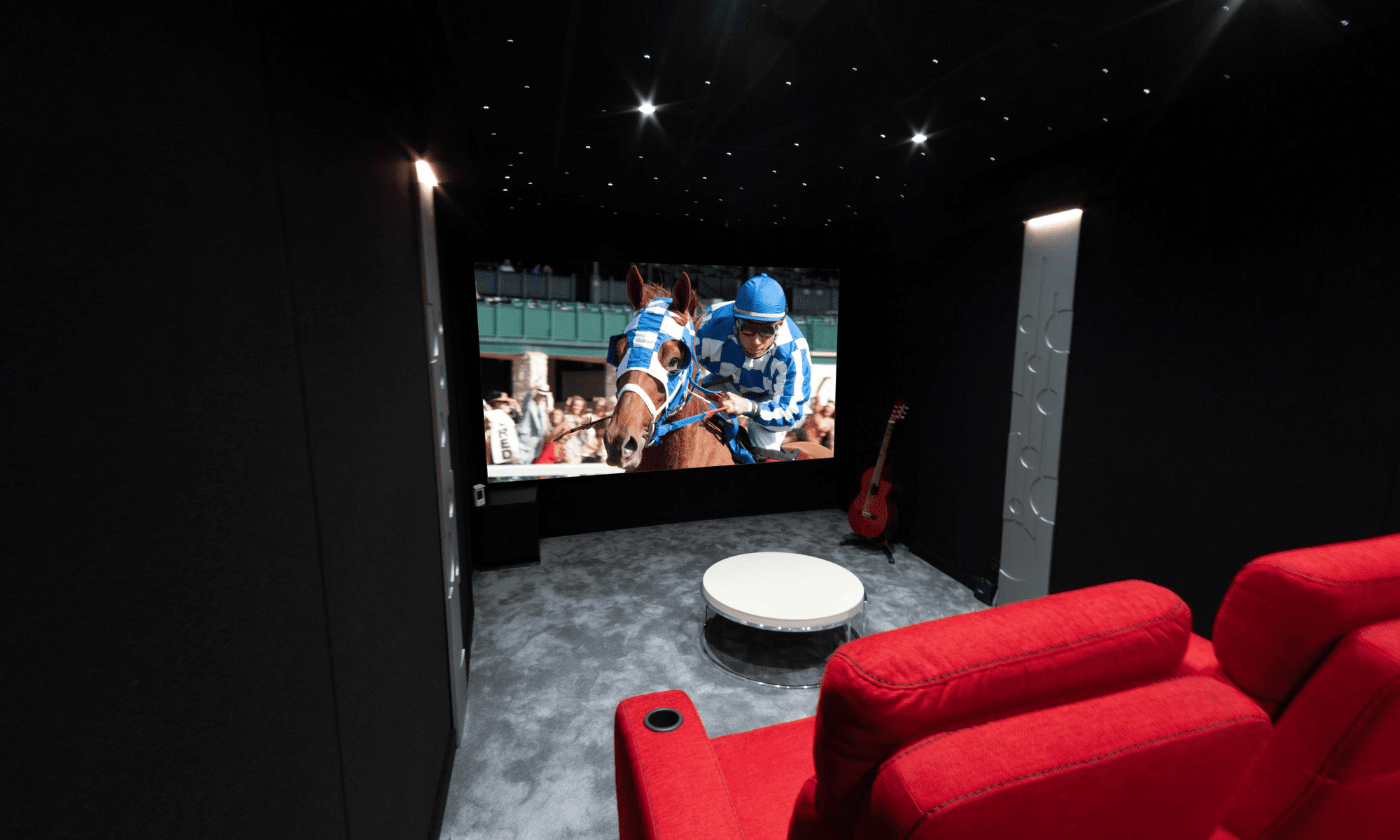 Salle de cinéma privée 18m2 avec 5 fauteuils en tissu rouge, panneaux décors thermoformés, ciel étoilé, spots, moquette grise à Cannes