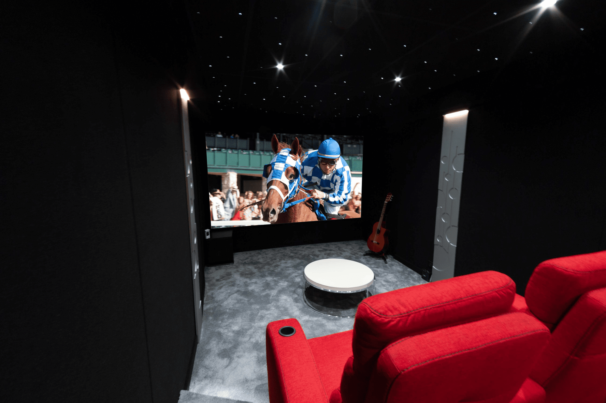 Salle de cinéma privée 18m2 avec 5 fauteuils en tissu rouge, panneaux décors thermoformés, ciel étoilé, spots, moquette grise à Cannes