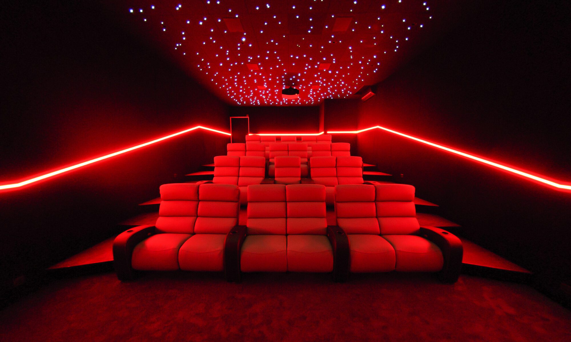 Grande salle de cinéma privée 70m2, 22 places avec fauteuils en cuir gris clair, avant-scène, ciel étoilé, spots, boiserie éclairée, bar avec cave à vin à Conakry