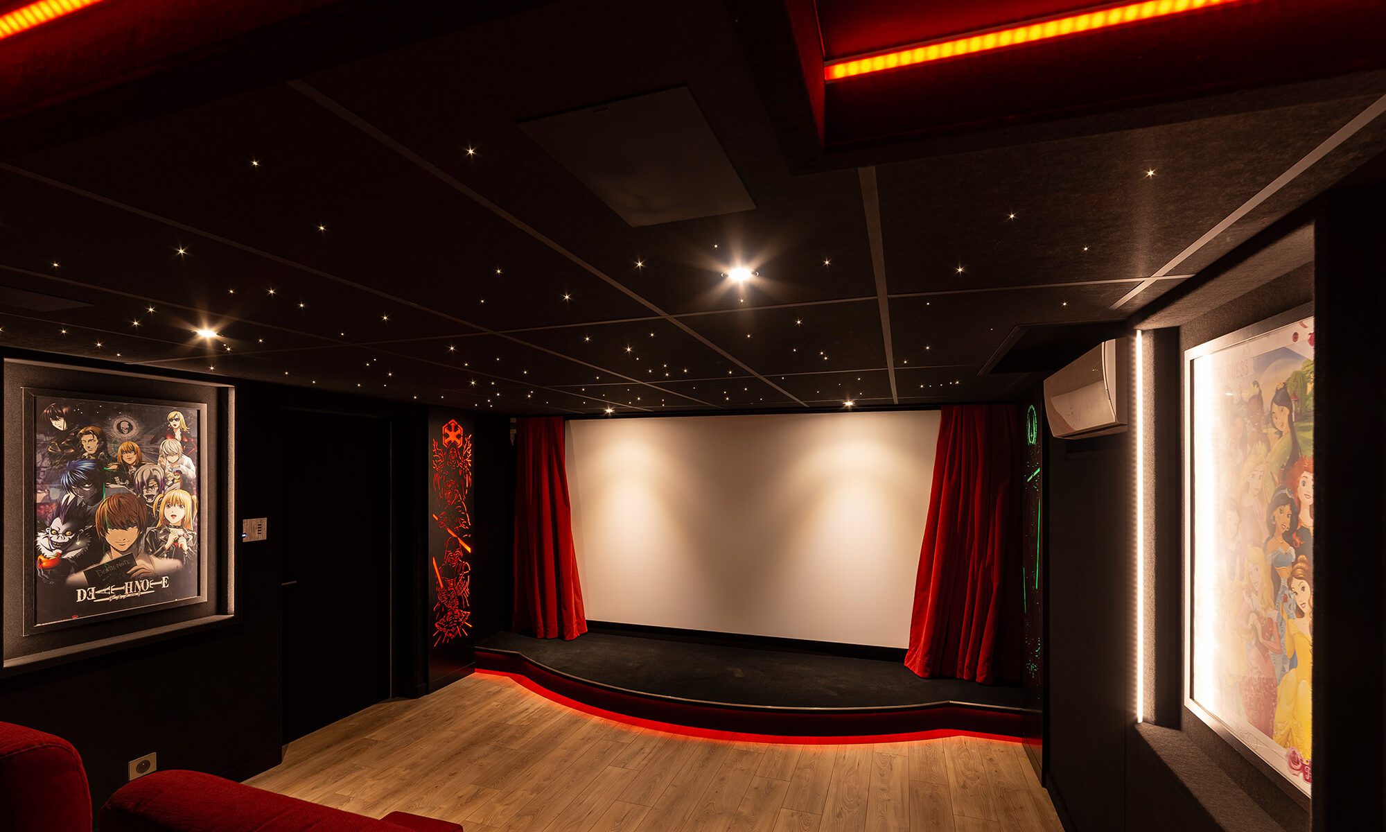 Salle de cinéma privée 27m2 avec 8 fauteuils en tissu rouge, parquet chêne, avant-scène, ciel étoilé, rideaux rouges et panneaux décor sur-mesure à Créteil