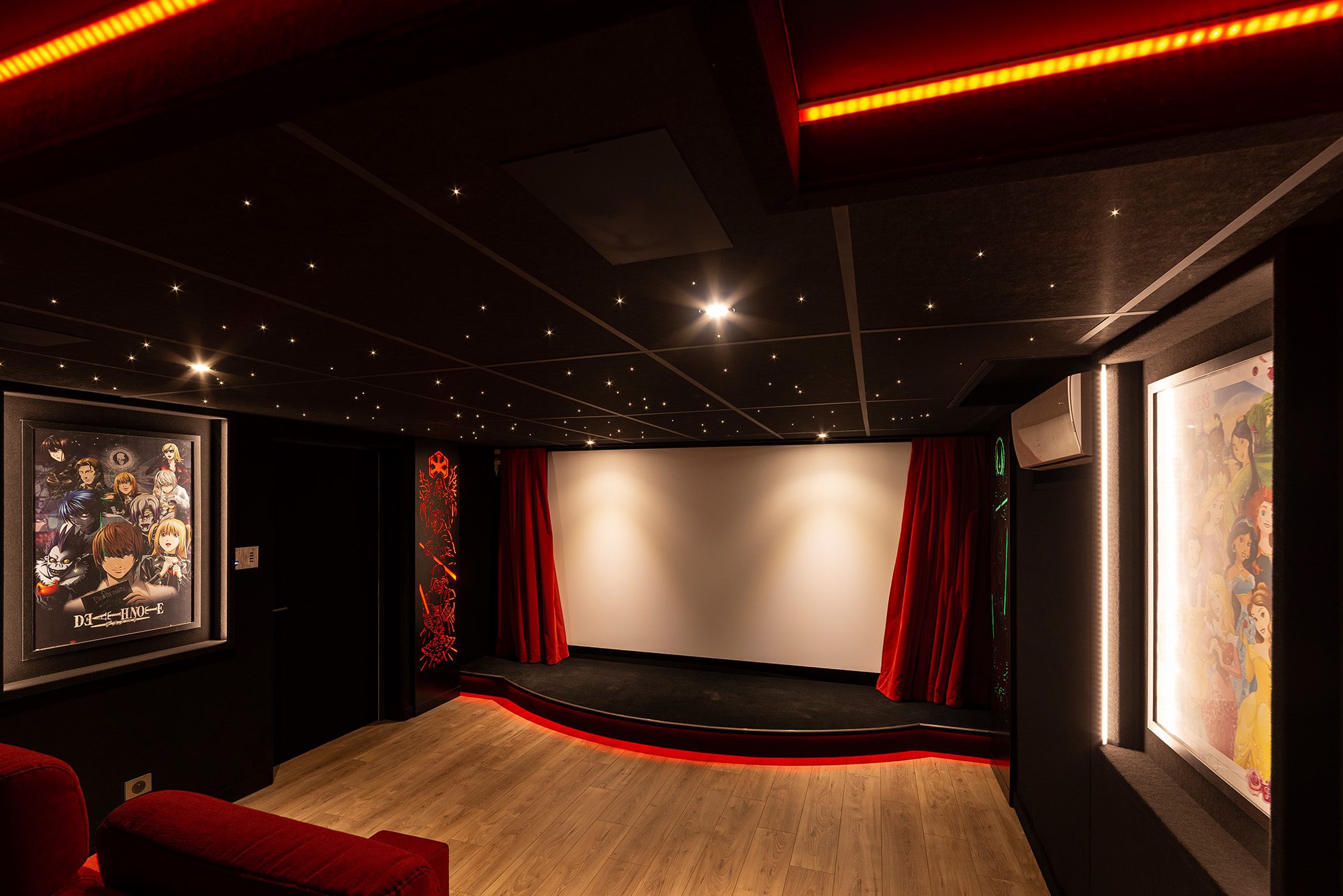 Salle de cinéma privée 27m2 avec 8 fauteuils en tissu rouge, parquet chêne, avant-scène, ciel étoilé, rideaux rouges et panneaux décor sur-mesure à Créteil