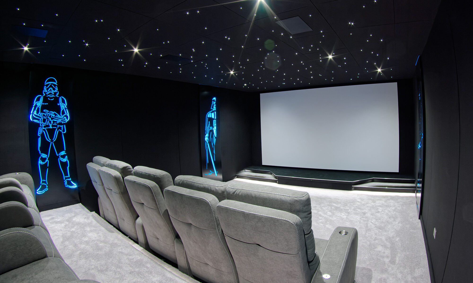 Salle de cinéma privée 33m2 avec 10 fauteuils en tissu gris, ciel étoilé, spots, panneaux décor lumineux Starwarsn, moquette grise à Orgeval