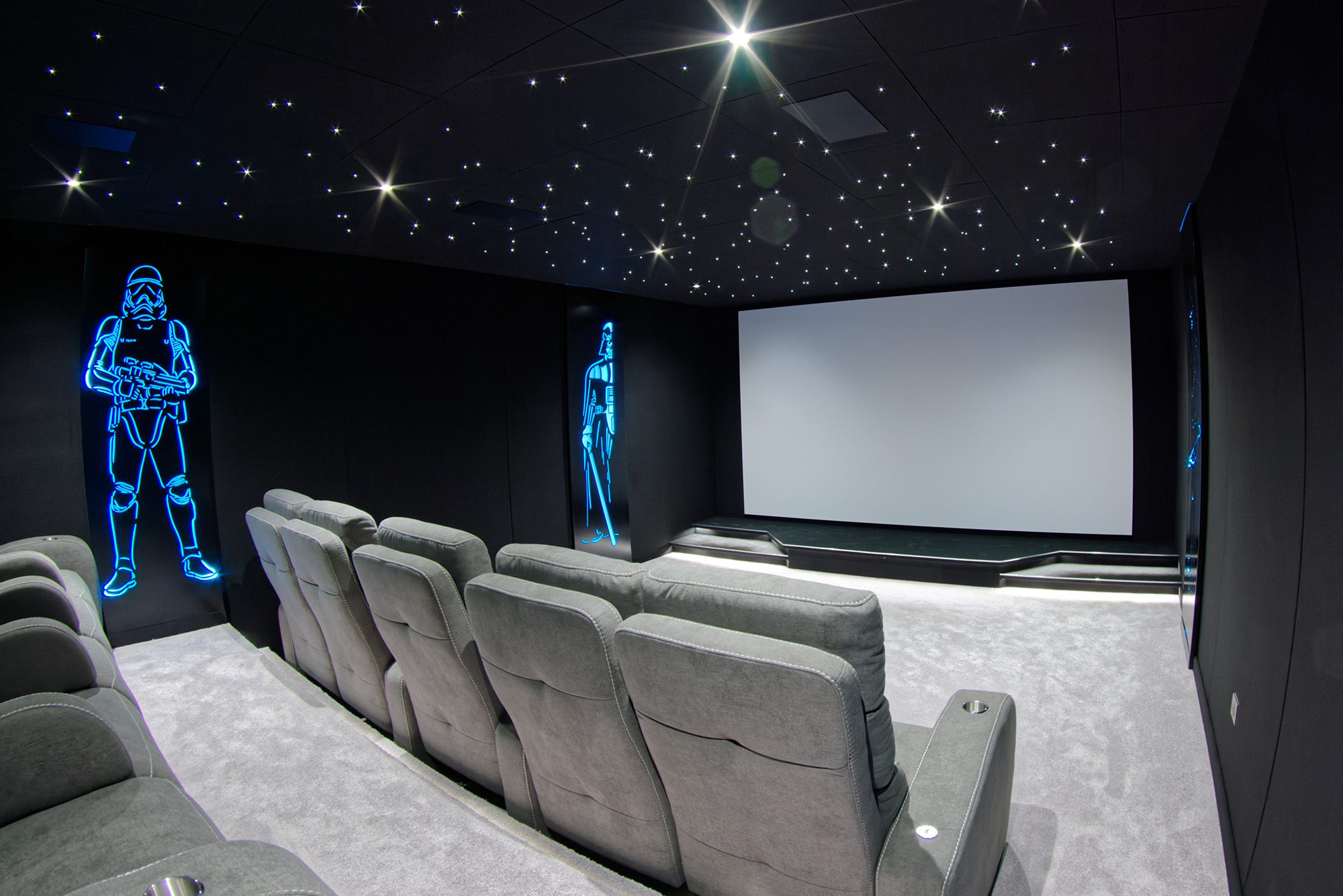 Salle de cinéma privée 33m2 avec 10 fauteuils en tissu gris, ciel étoilé, spots, panneaux décor lumineux Starwarsn, moquette grise à Orgeval