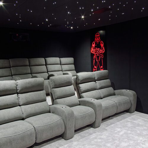 Salle de cinema privée grise avec 10 places, plafond étoilé et décoration lumineuse rouge Starwars