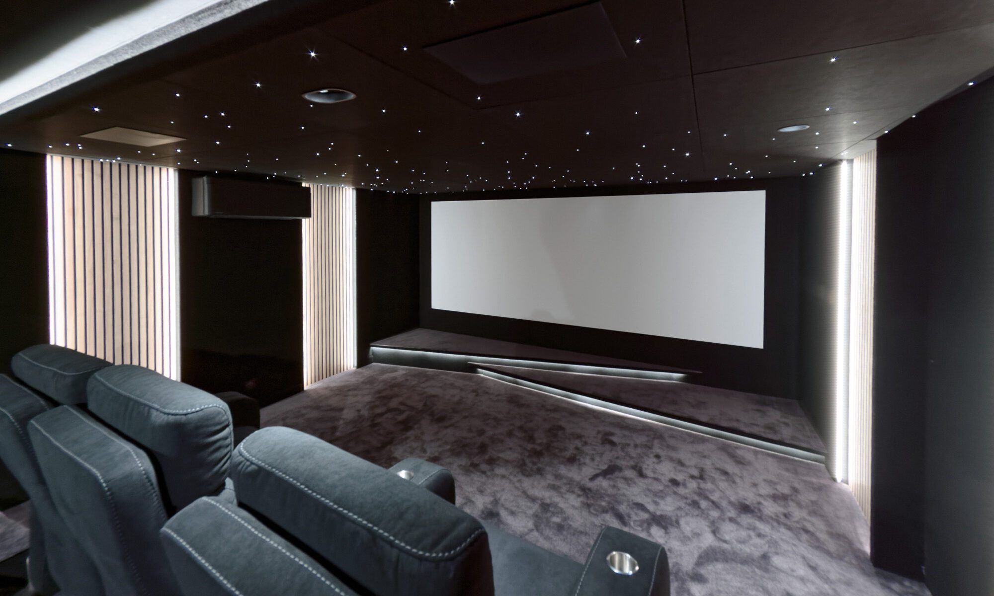 Salle de cinéma privée 22m2 avec 7 fauteuils en tissu en gris, ciel étoilé, spots, panneaux décor tasseaux de bois éclairés, moquette grise et double estrade à Rueil