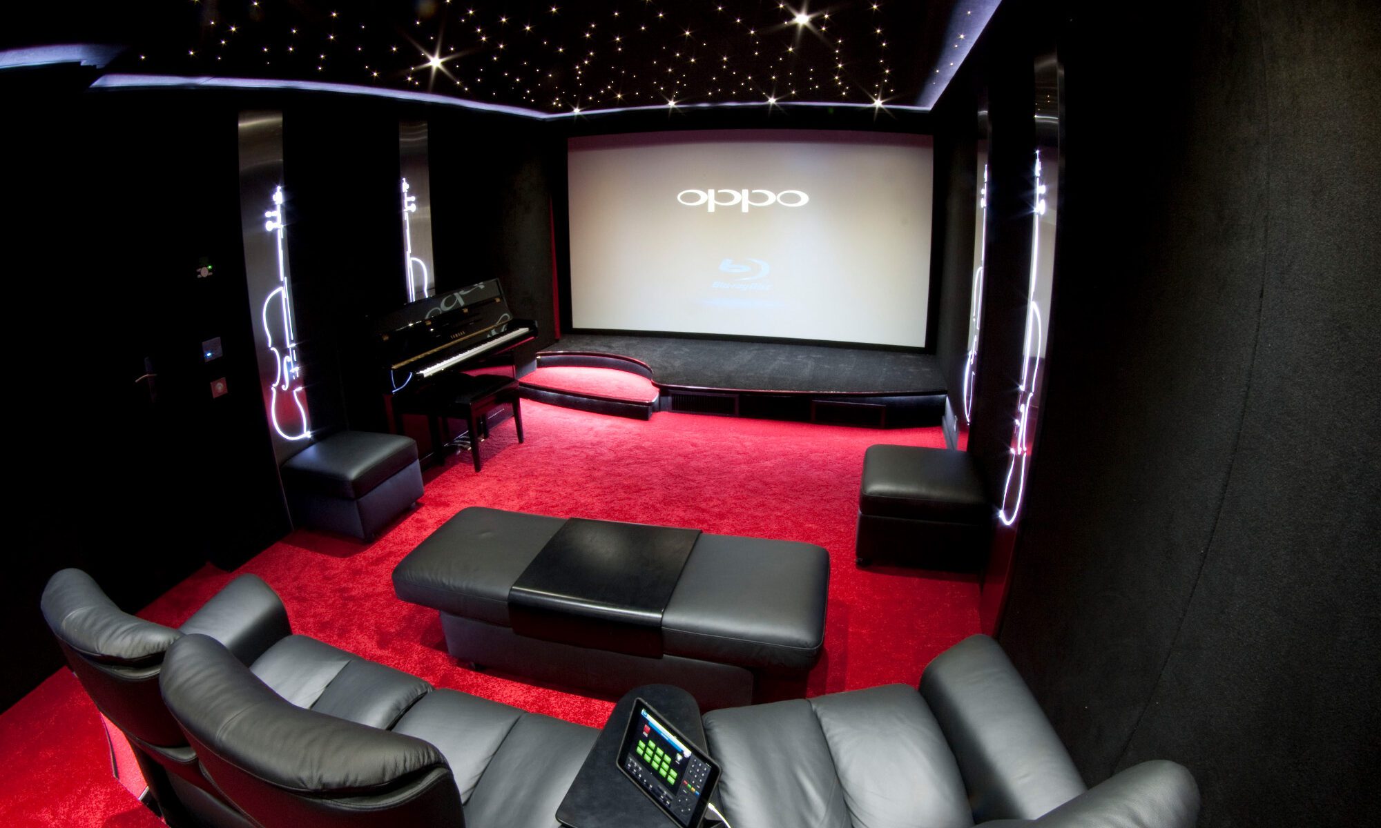 Salle de cinéma privée 32m2 avec 7 fauteuils en cuir noir, panneaux décors métalliques rétroéclairés, corniche lumineuse, avant-scène à Le Raincy