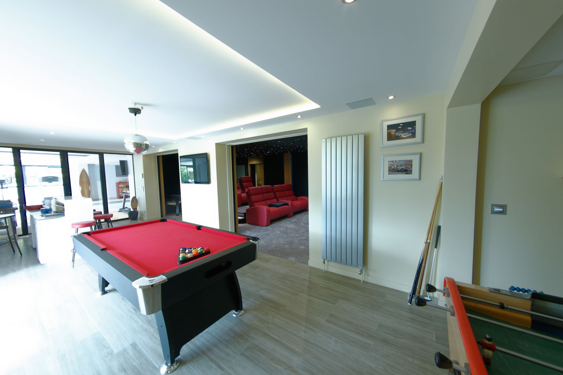 Billard rouge et baby-foot devant une salle cinéma équipée de fauteuils relax