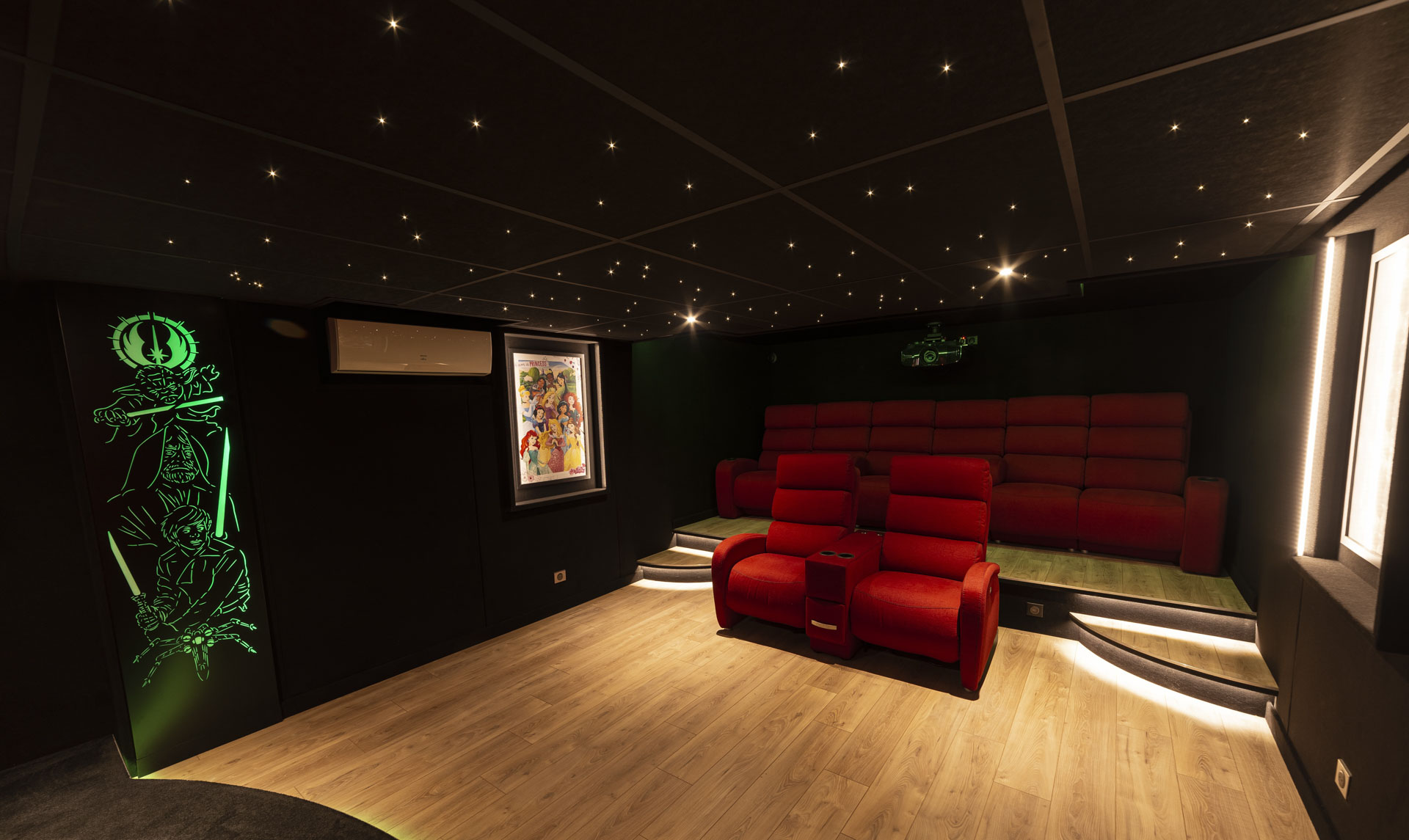 Deux fauteuils relax rouges devant une banquette arrière de six places dans un cinéma privé