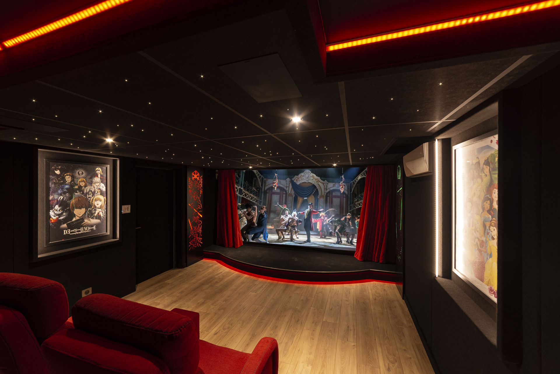 Vue générale d’une salle de cinéma privée à Montreuil avec écran de 3 m, rideaux rouges et plafond étoilé