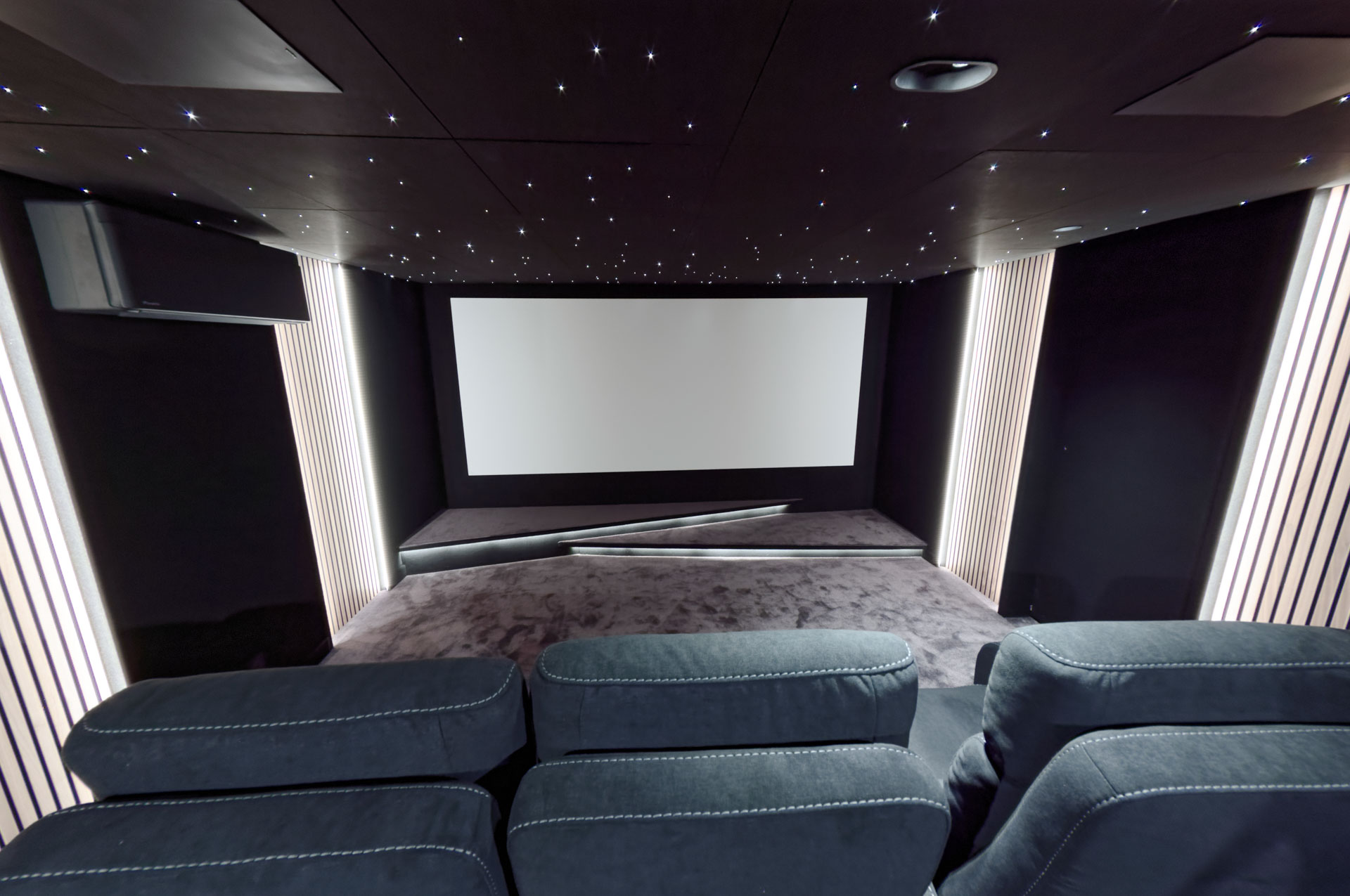 Panneaux verticaux en tasseaux de bois rétroéclairés dans une salle de cinéma privée